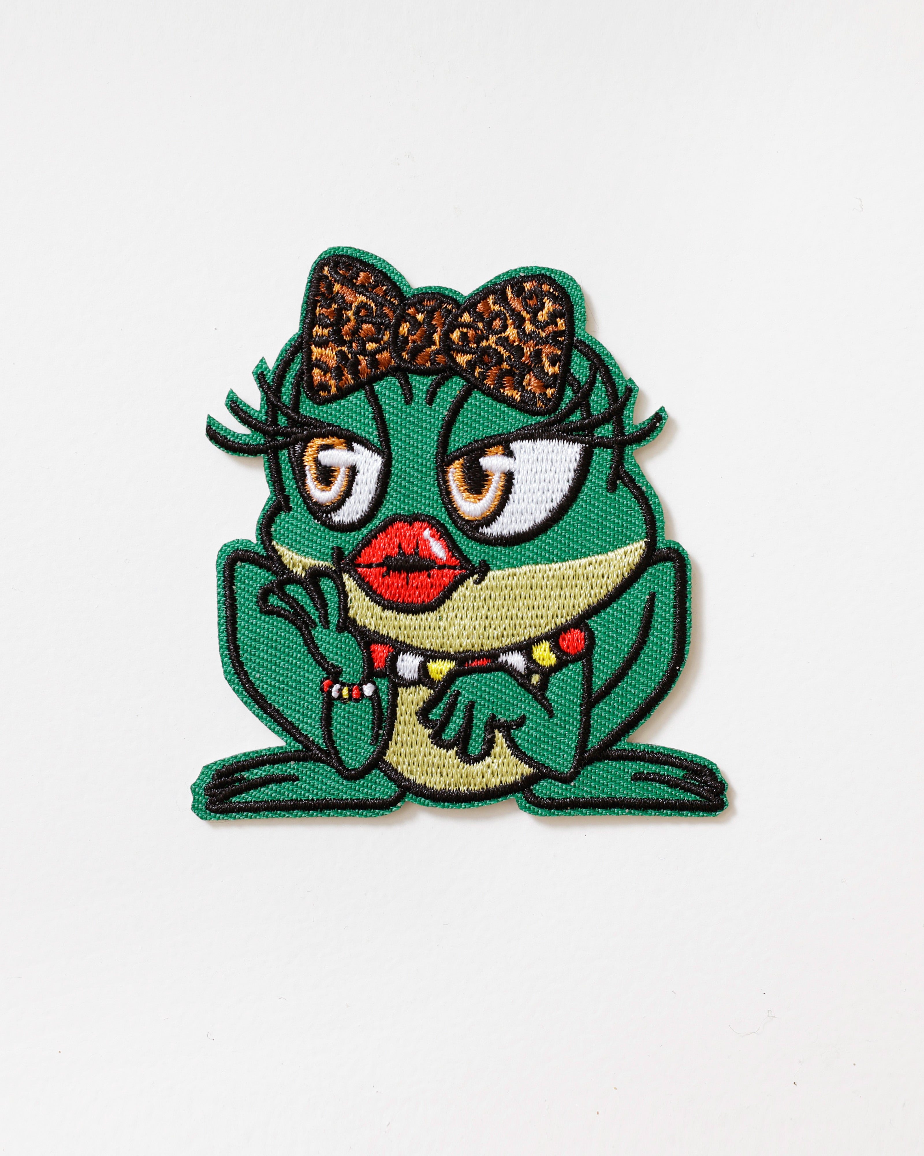 Embleem Oetel Diva – Ondeugende Kikker met Strik